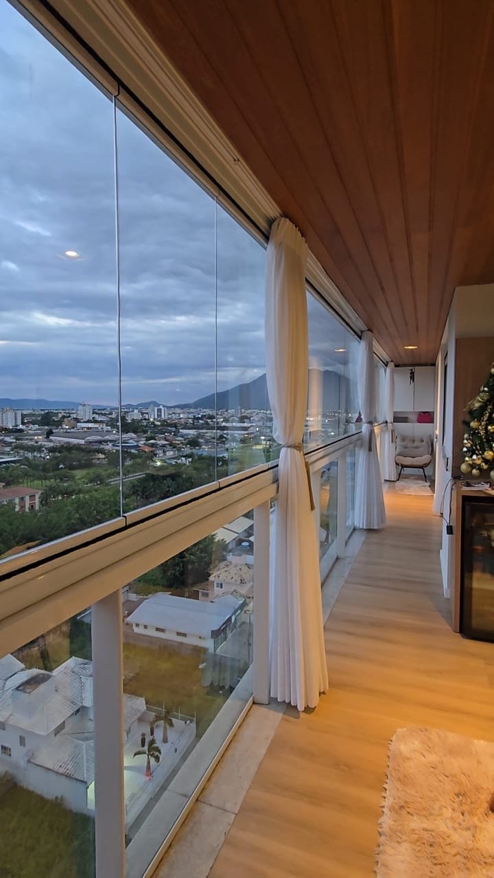 Sacada residencial fechada com grandes painéis de vidro e vista para a cidade